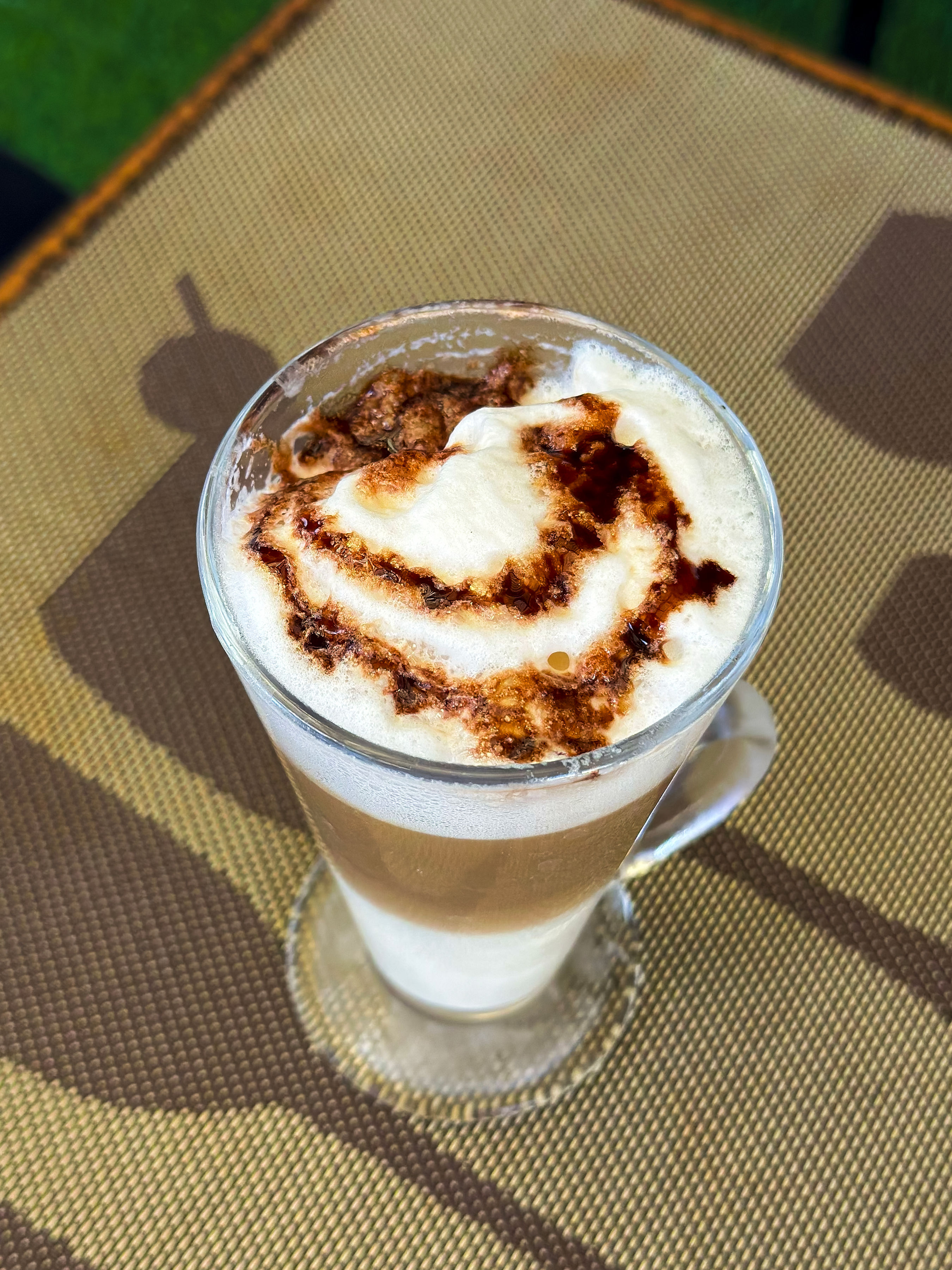 Layered coffee with a foamy topping in a glass mug
